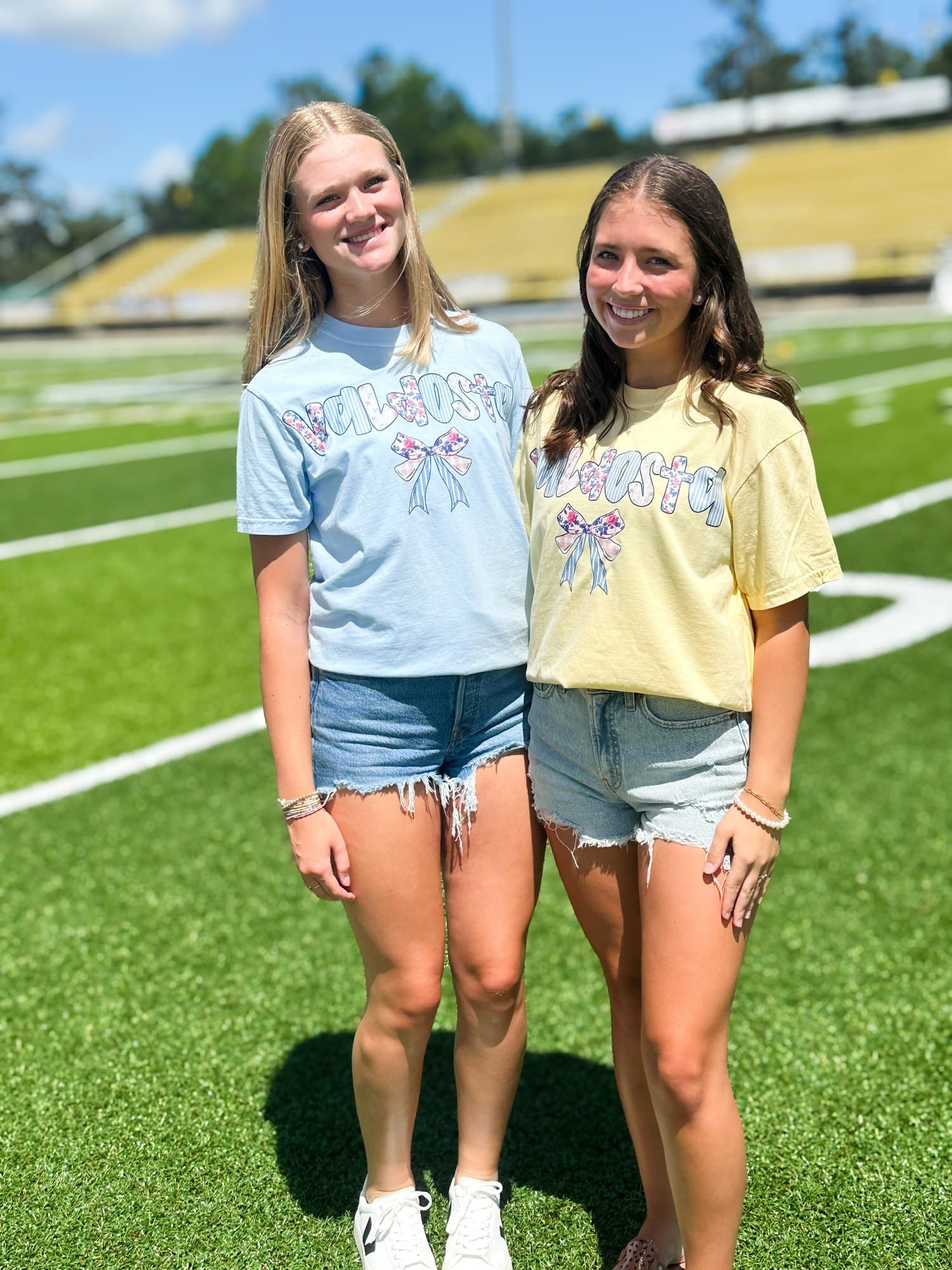 Two Valdosta fans on the field in pastel Valdosta bow tees